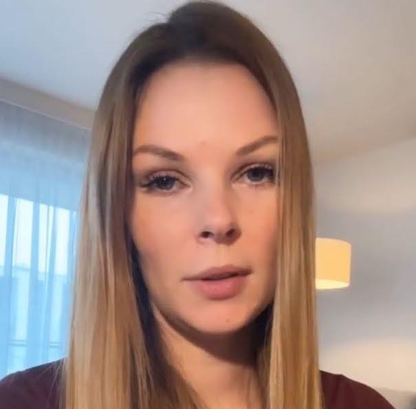 Małgorzata Tomaszewska prowadząca program telewizyjny, dynamiczna poza na tle studia.