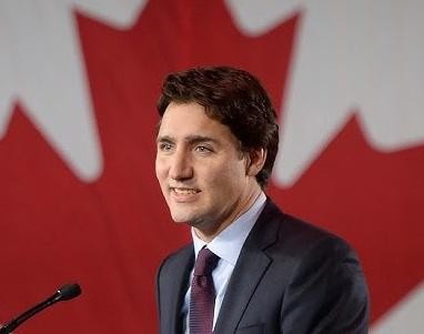 Justin Trudeau uśmiechnięty i rozmawiający z ludźmi podczas publicznego wydarzenia, ukazujący jego dostępność i zaangażowanie.