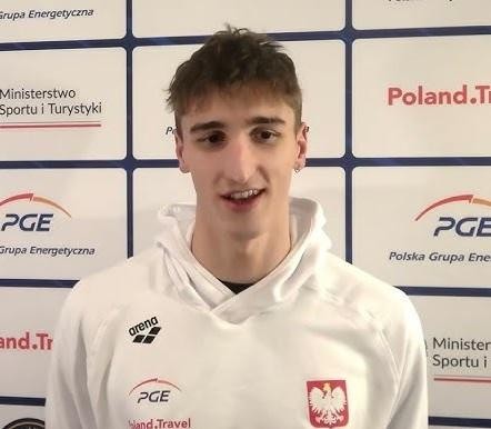 Ksawery Masiuk podczas wyścigu w stylu grzbietowym, z widocznym skupieniem i rozpryskującą się wodą.