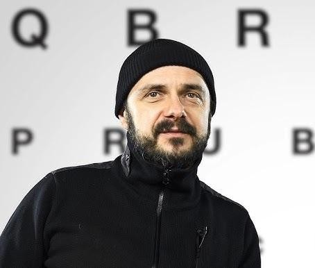 Arkadiusz Jakubik, wokalista zespołu Dr Misio, śpiewający z pasją do mikrofonu na scenie, w dynamicznym oświetleniu koncertowym.