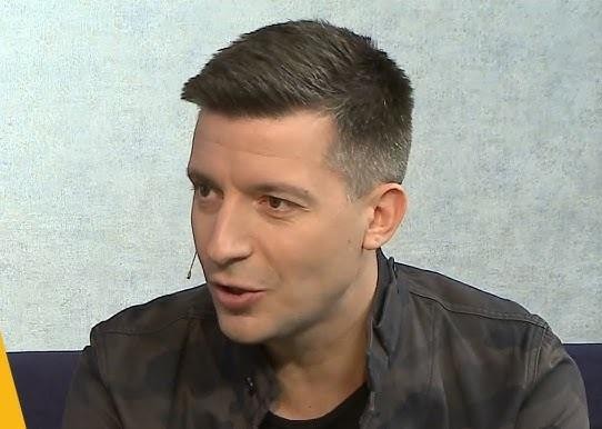 Michał Cessanis korzystający z telefonu, na ekranie widać treści związane z podróżami i Instagramem, w tle subtelne elementy podróżnicze.