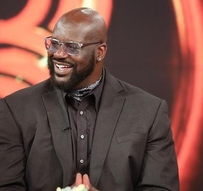 Shaquille O'Neal w stroju akademickim, symbolizującym jego osiągnięcia edukacyjne.