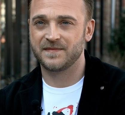 Mateusz Gessler podczas gotowania w profesjonalnej kuchni, skupiony na przygotowywaniu dania.