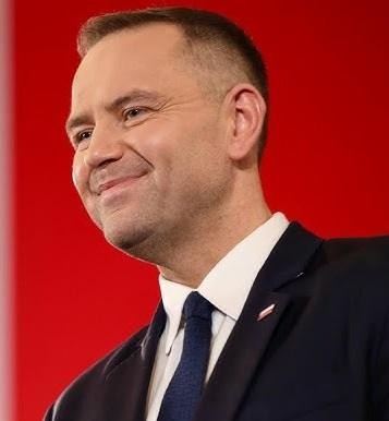 Karol Nawrocki w Muzeum II Wojny Światowej, w tle regały z książkami.