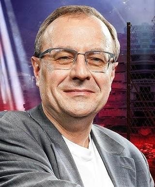 Antoni Dudek podczas wystąpienia publicznego lub wykładu, w otoczeniu nawiązującym do jego działalności naukowej i medialnej.